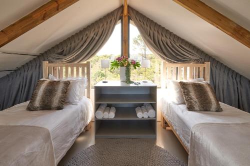 two beds in a room with a window at Treedom Villas and Vardos in Wilderness