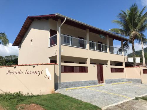 a building with a palm tree in front of it at Recanto Lorenzi - Apartamentos in Ubatuba
