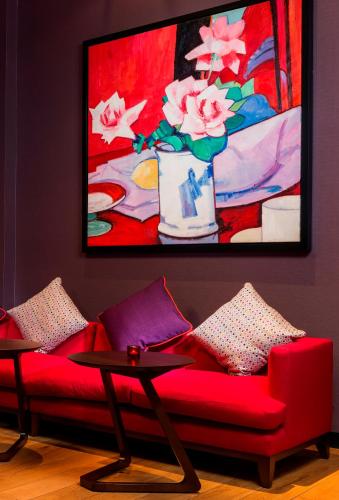a red couch with a table and a painting at Park Inn by Radisson Aberdeen in Aberdeen