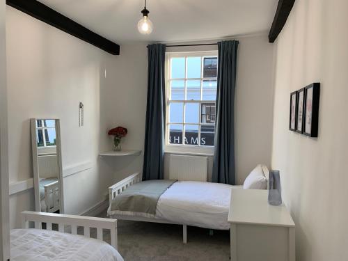 a small room with two beds and a window at 1 Central Chambers in Stratford-upon-Avon