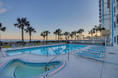 a swimming pool with chairs and the ocean in the background at 11-th Floor OcenView w Balcony cozy condo at Boardwalk Resort in Myrtle Beach