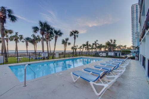 a swimming pool with lounge chairs and palm trees at 11-th Floor OcenView w Balcony cozy condo at Boardwalk Resort in Myrtle Beach