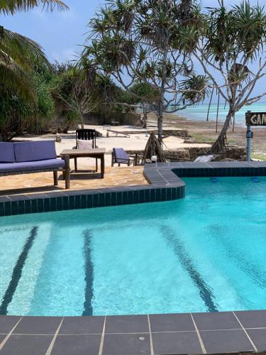 a swimming pool with a table and chairs next to a beach at Game Fish Lodge in Nungwi