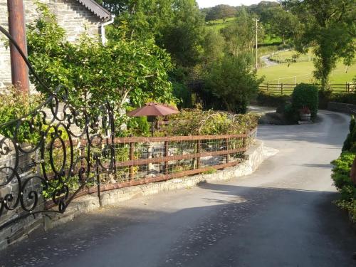 a fence with an umbrella on the side of a road at Mill Cottage in Llanddeiniol