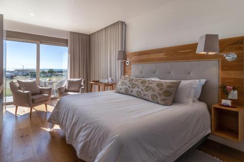 a bedroom with a large white bed and a chair at Oceans Guest House & Luxurious Apartments in Struisbaai