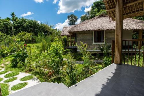 a house with a thatched roof and a garden at Balishira Resort Ltd. in Sreemangal