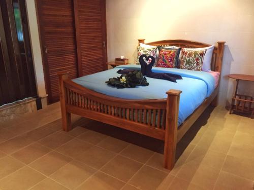 a bedroom with a wooden bed with blue sheets and pillows at Krabi Villa Phu Khao Private Resort in Klong Muang Beach