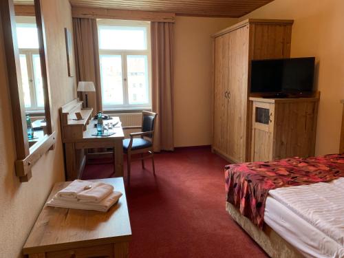 a hotel room with a bed and a desk and a television at Hotel Goldner Löwe in Stolpen