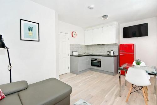F3 Greek Street by City Living London في لندن: غرفة معيشة مع أريكة وثلاجة حمراء