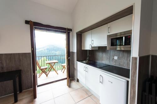 a kitchen with white cabinets and a balcony with a table at Gorosarri in Escoriaza
