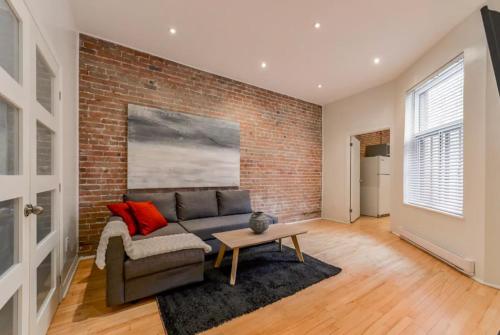 a living room with a couch and a brick wall at Le Duplex VIP in Montréal