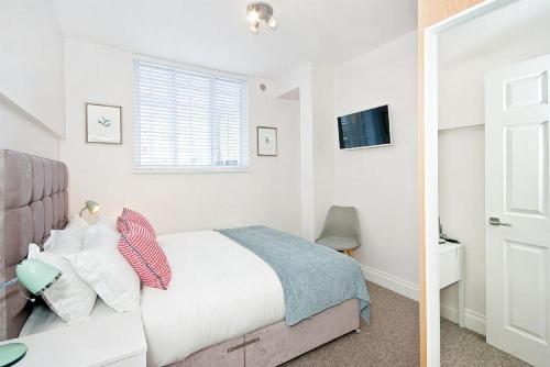 Habitación blanca con cama y espejo en F1 Greek Street by City Living London en Londres