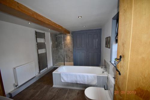 ein großes Bad mit einer Badewanne und einer Dusche in der Unterkunft White Hall Farm in Leamington Spa