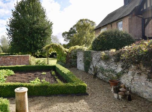 a garden with bushes and a stone wall at White Hall Farm in Leamington Spa