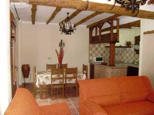 sala de estar con sofá naranja y mesa en Casa Rural-Apartamento El Lebrillero, en Zahara de la Sierra