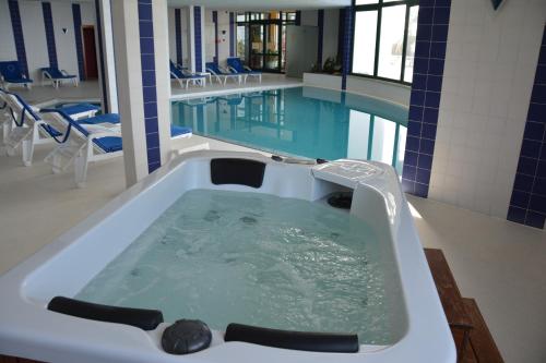 a bath tub filled with water next to a swimming pool at Hotel Jardim Atlantico in Calheta