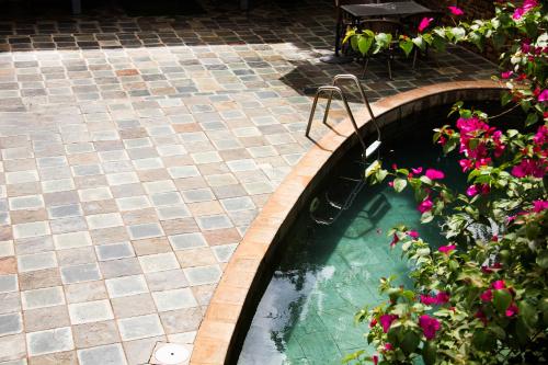 a pool of water with pink flowers on a patio at Hotel Bougainviller in Kampala
