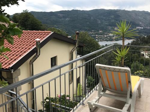 a chair sitting on a balcony with a view at Casa de Casarelhos - Andar da Moradia com terraço - Vistas rio - "Gerês" in Geres