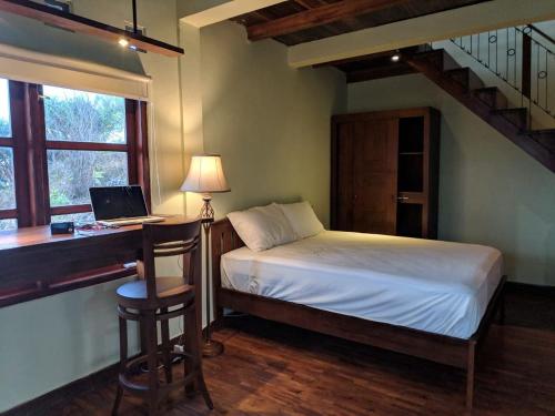 Schlafzimmer mit einem Bett und einem Schreibtisch mit einem Laptop in der Unterkunft Fam Sugiono Cottage in Kemadang