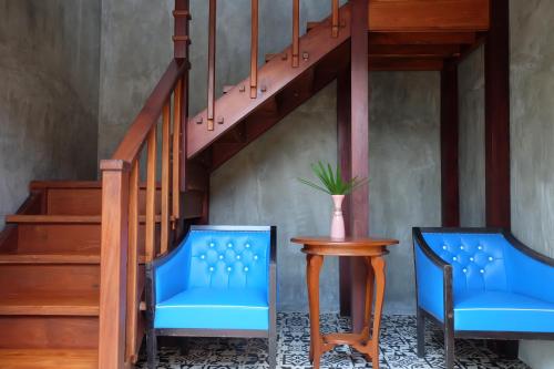 two blue chairs and a table next to a staircase at House Of Passion Amphawa in Amphawa