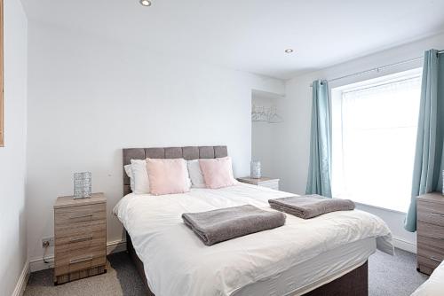 a white bedroom with a large bed with pink pillows at Amazing views of the City in Swansea
