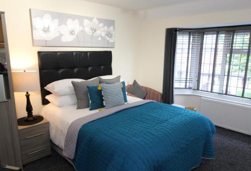 a bedroom with a large bed with a blue blanket at Holcombe House in Wolverhampton