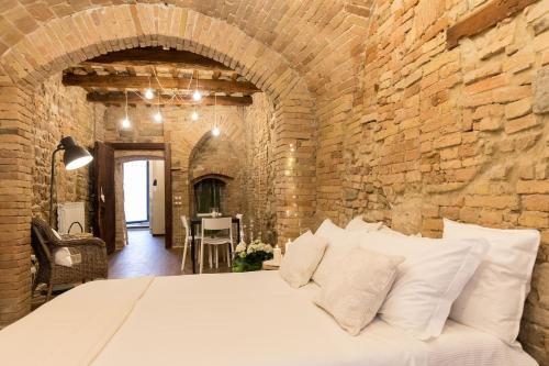ein Schlafzimmer mit einem großen Bett in einer Ziegelwand in der Unterkunft Il Vicolo Di Porta Pesa in Perugia