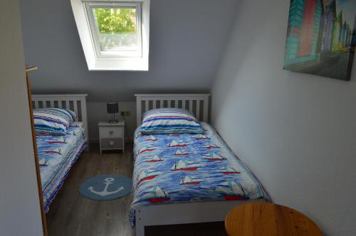 ein kleines Schlafzimmer mit zwei Betten und einem Fenster in der Unterkunft Ferienhaus Heimathafen Neßmersiel in Neßmersiel