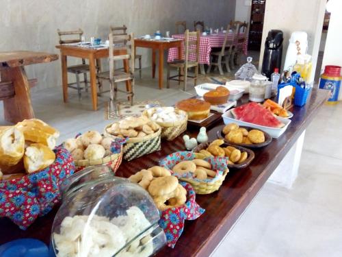 uma mesa longa com muitos tipos diferentes de pastelarias em Pousada Ipoema em Ipoema