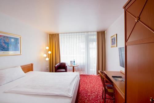 a hotel room with a bed and a desk at Caravelle Hotel im Park in Bad Kreuznach