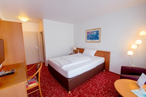 a hotel room with a bed and a desk and a table at Caravelle Hotel im Park in Bad Kreuznach