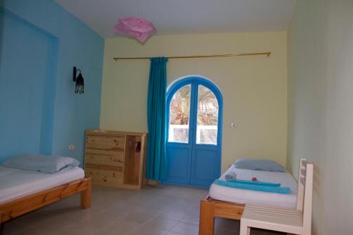 a bedroom with two beds and a blue door at El Primo Hotel Dahab in Dahab