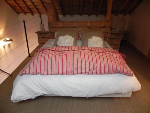 a large bed with a red and white striped comforter at Le Grand Gîte in Dorengt