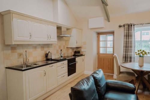 Una cocina con gabinetes blancos y una mesa y un sofá. en Dunlin, en Belford