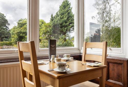 a wooden table with two chairs and a table with two cups at Windermere Park B&B inc Free off-site Health Club in Windermere