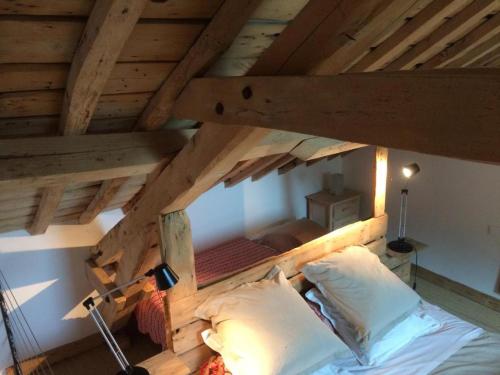 a bed in a room with a wooden ceiling at Le Grand Gîte in Dorengt