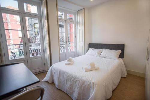 um quarto com uma cama branca com duas toalhas em Oporto Cool - Praça da Batalha em Porto