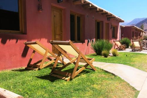 Casatilcara Cabañas في تيلكارا: كرسيان خشبيان يجلسان خارج المنزل