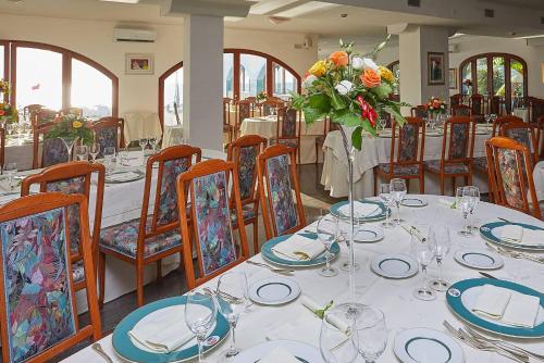 a dining room with a table with plates and flowers on it at Hotel Poseidon in Diamante
