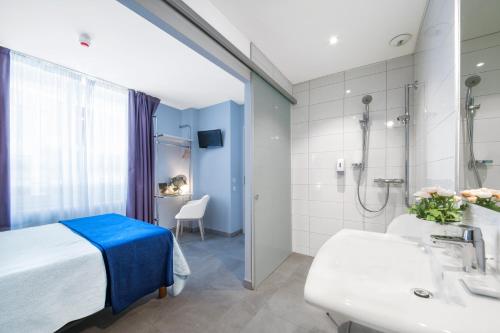 a bathroom with a bed and a shower and a sink at H&ocirc;tel Le Saphir in Biarritz