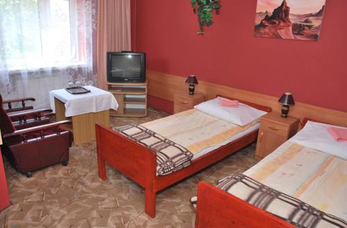 a hotel room with two beds and a television at Hotel Skarpa in Sejny