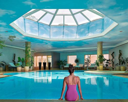 a woman sitting in front of a swimming pool at Four Seasons Hotel Cairo at Nile Plaza in Cairo