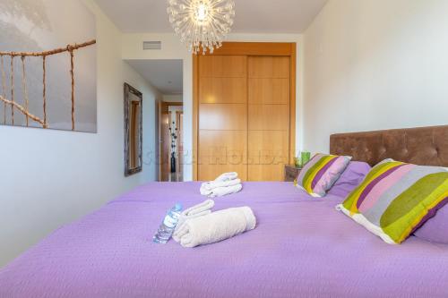 a bedroom with a purple bed with towels on it at Residencial Duquesa 18 in Manilva