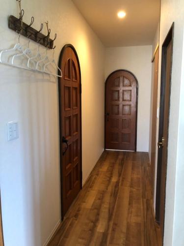an empty hallway with two doors and wooden floors at Amami Weekly House Nico Nico Nazeko-ten in Amami