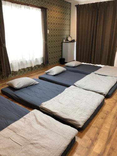 1 dormitorio con 3 camas en una habitación en Amami Weekly House Nico Nico Nazeko-ten en Amami