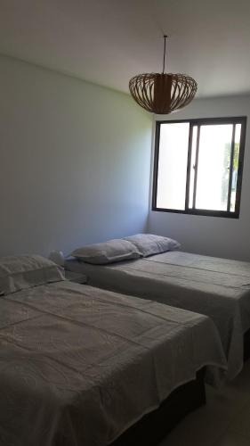 two beds in a room with a window at Carneiros Beach Resort in Tamandaré