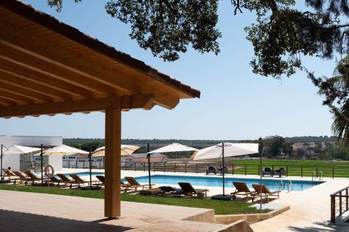 a swimming pool with lounge chairs and umbrellas at Casas Do Rio Sado - Sado River Country Retreat in Santa Margarida do Sado