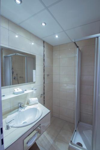 a white bathroom with a sink and a shower at Caravelle Hotel im Park in Bad Kreuznach