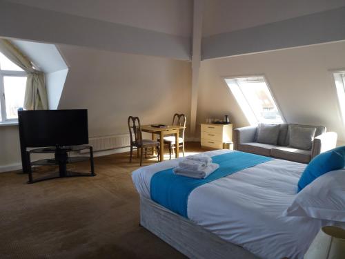 a bedroom with a bed and a tv and a table at Boathouse Hotel in Hythe