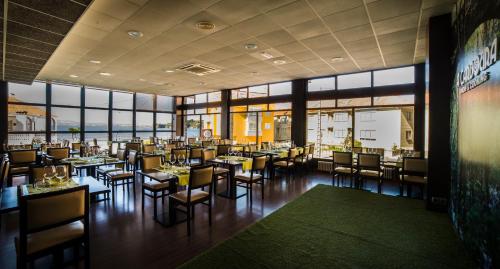 a restaurant with tables and chairs and windows at Hotel Crisol de las Rías in Miño
